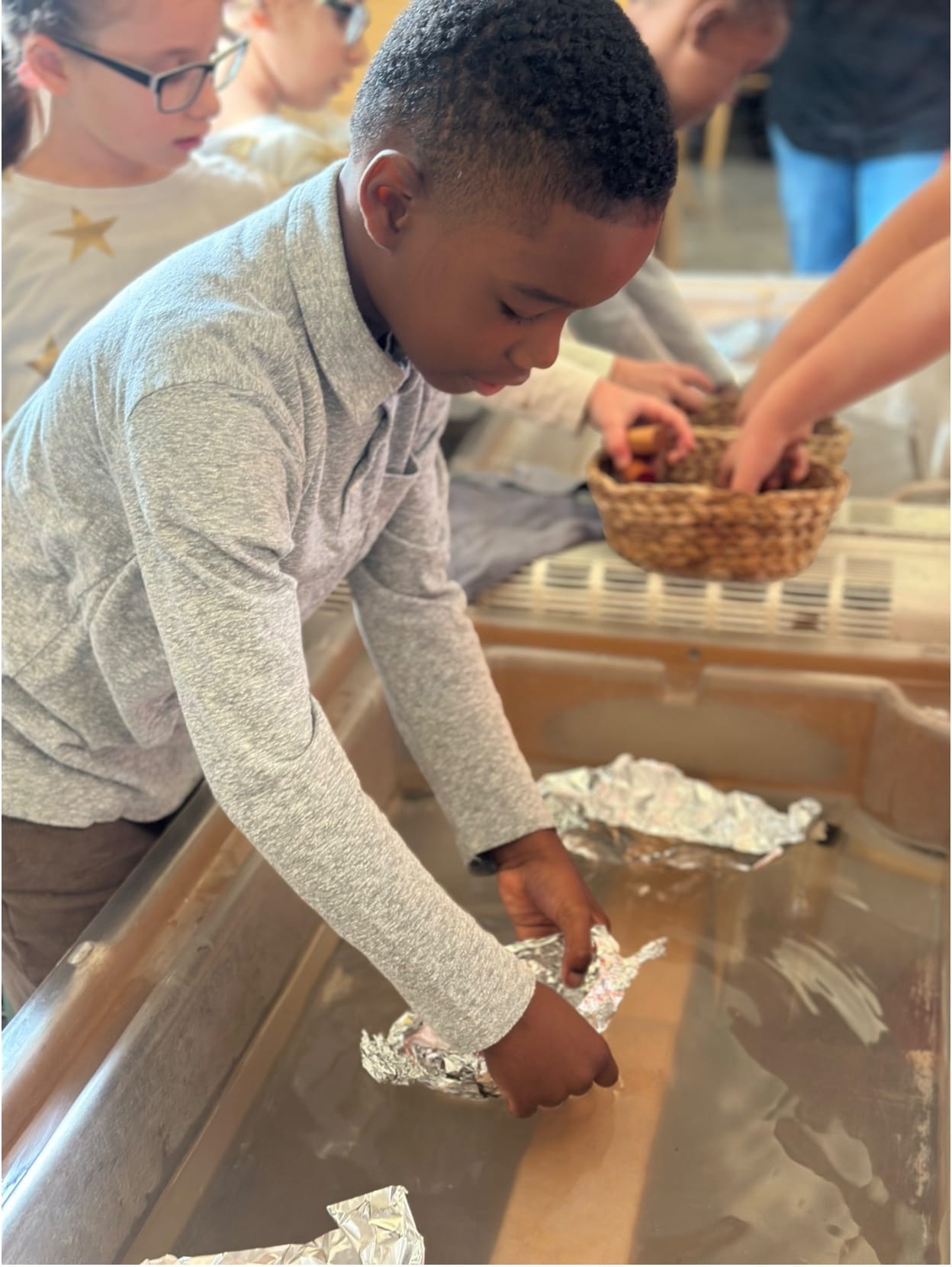 A student launches a foil boat in the water table during a science activity