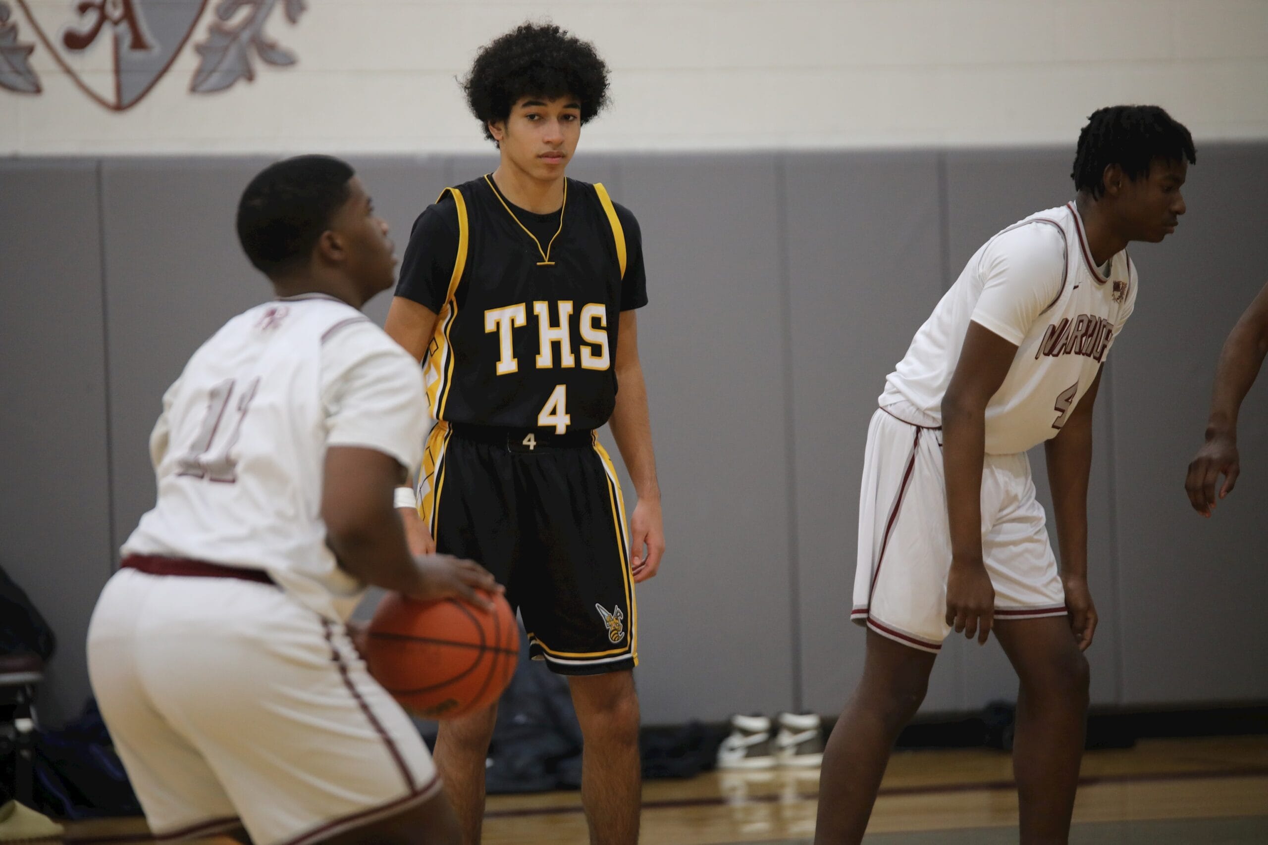 A Hudson basketball player in the black and gold THS jersey watches the play during a game