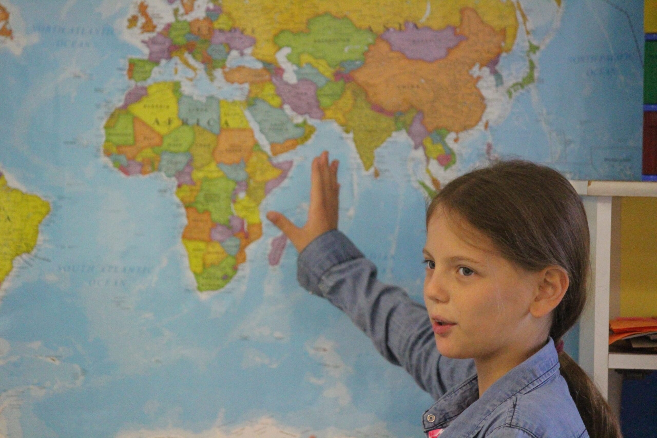 A student points to Africa on a world map during a geography lesson