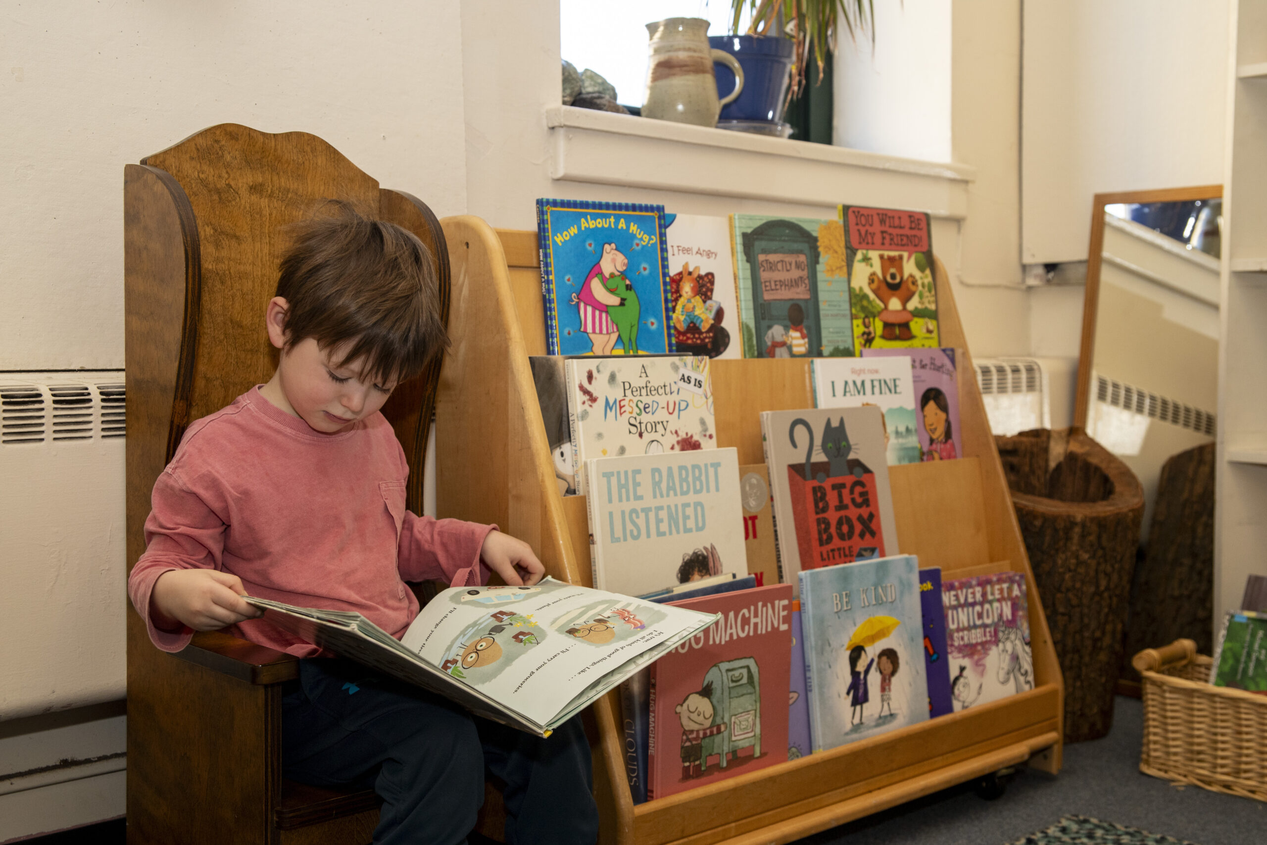 A young student reads a picture book beside the classroom book display